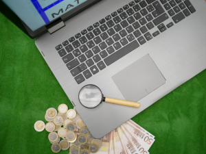 Money and magnifier on a laptop illustrating the concept of online sports betting.