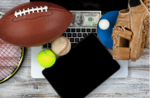 Different sports goods, tablet, laptop, and a dollar bill